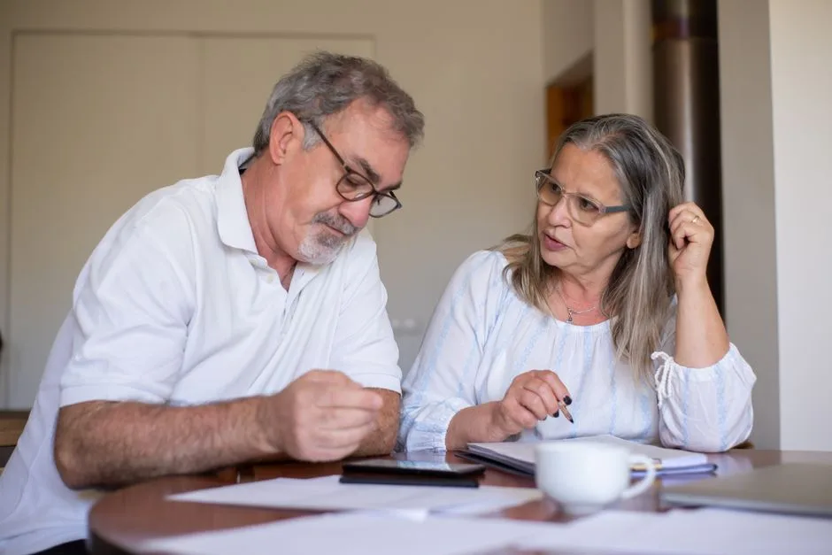Un couple de jeunes retraités relit ses documents à la table de la cuisine